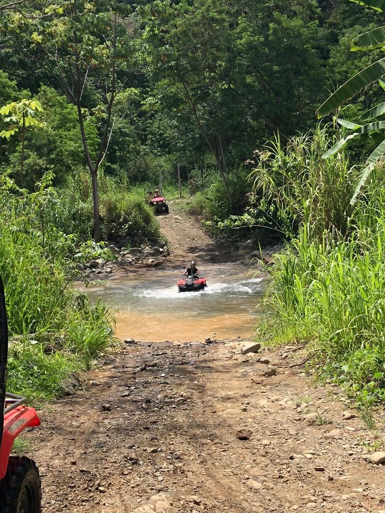 A guest riding an ATV across a jungle river crossing