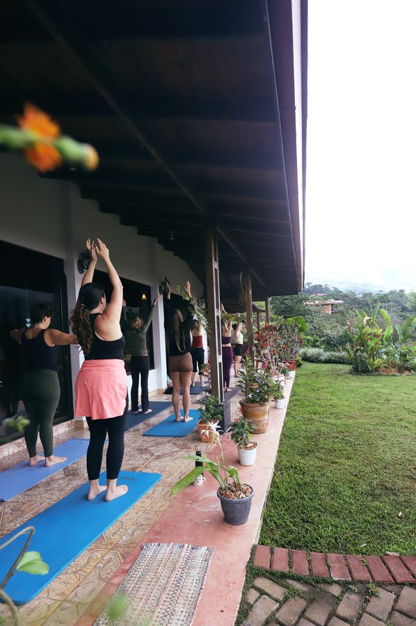 A group practicing yoga together on an open-air porch