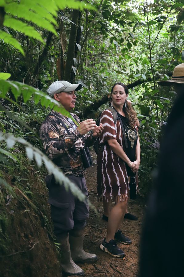 A guide sharing something with a guest on a rainforest trail
