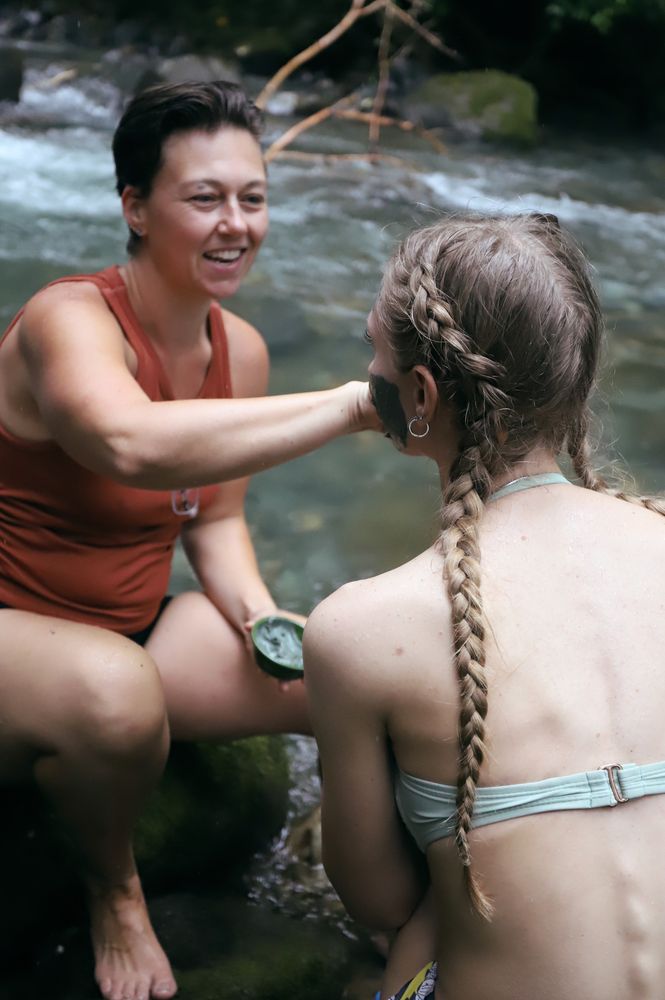 A facilitator applying clay mask during a river ceremony