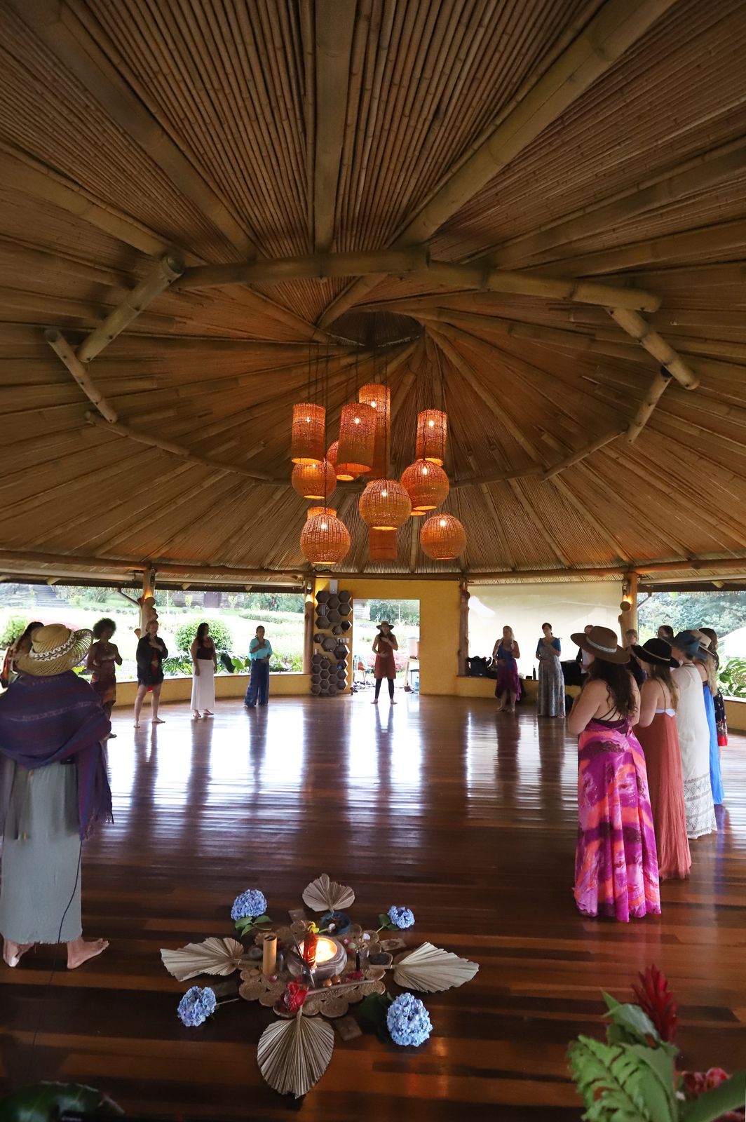A group of women gathered in a candlelit bamboo pavilion during a retreat ceremony